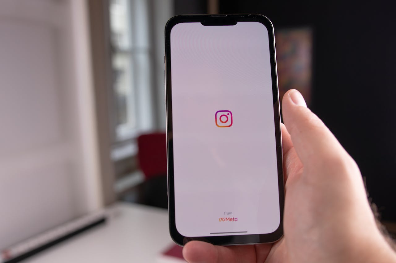 Auf dem Bildschirm des Telefons ist das Instagram-Symbol zu sehen. Es zeigt eine stilisierte Kamera in verschiedenen Farben auf einem quadratischen Hintergrund