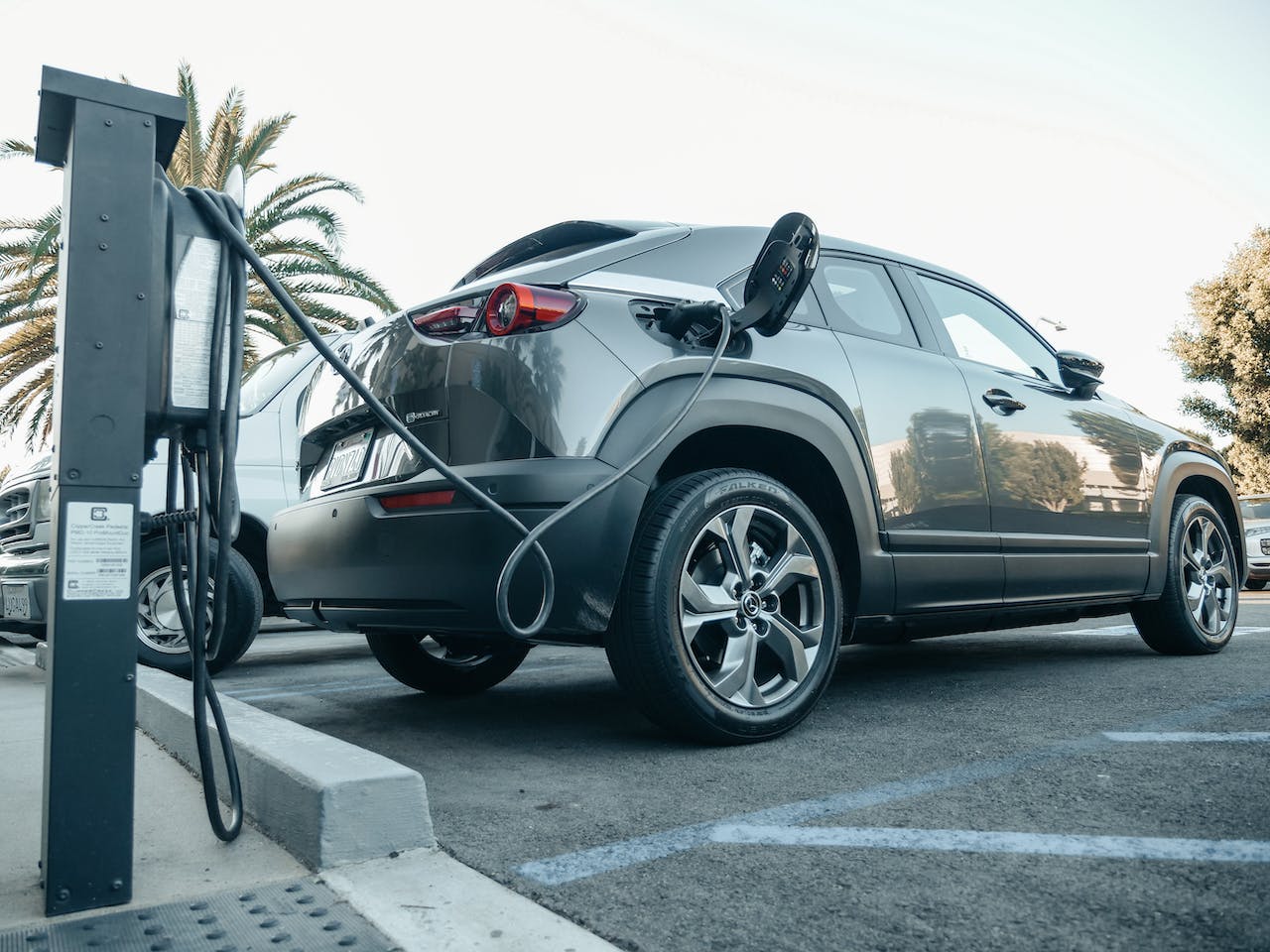Ein elektrisches Auto gleitet geräuschlos über die Straße, während es von einer Ladestation aufgeladen wird. Seine umweltfreundliche Technologie verspricht eine nachhaltige Zukunft