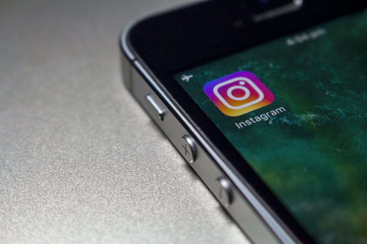Auf dem Bild ist das Instagram-Symbol auf dem Bildschirm eines Smartphones zu sehen. Die ikonische Kamera und der farbenfrohe Hintergrund repräsentieren die beliebte Social-Media-Plattform